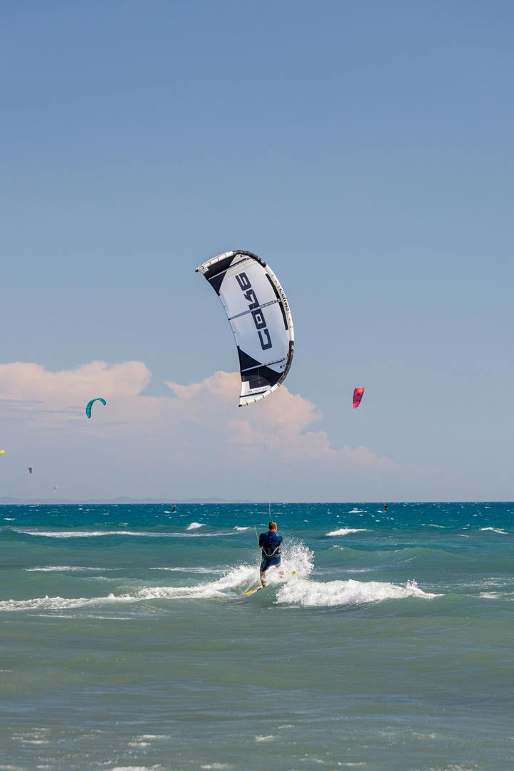 Island scenery, sunny beach, tourists paragliding on the sea.